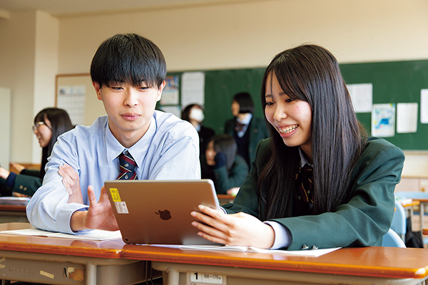 タブレットを見ながら授業を受ける男子生徒と女子生徒二人